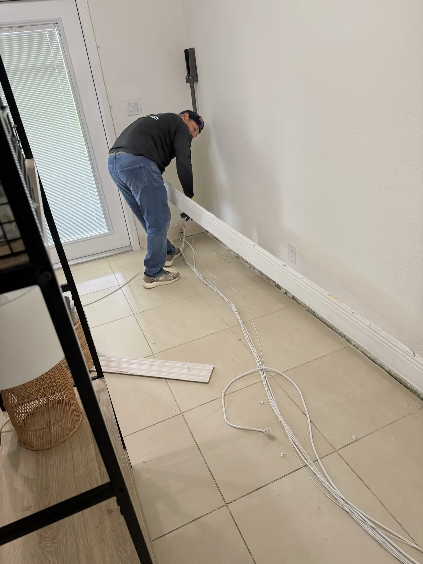 GXG crew installing baseboard trim in a Homestead, FL living room