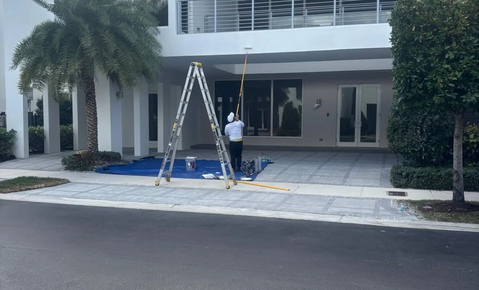GXG Remodeling painter on ladder painting a Homestead, FL home exterior